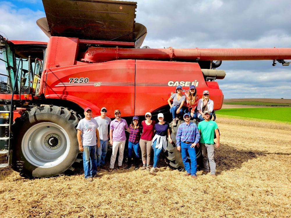 Indigo community gathered in front of a tilling machine.